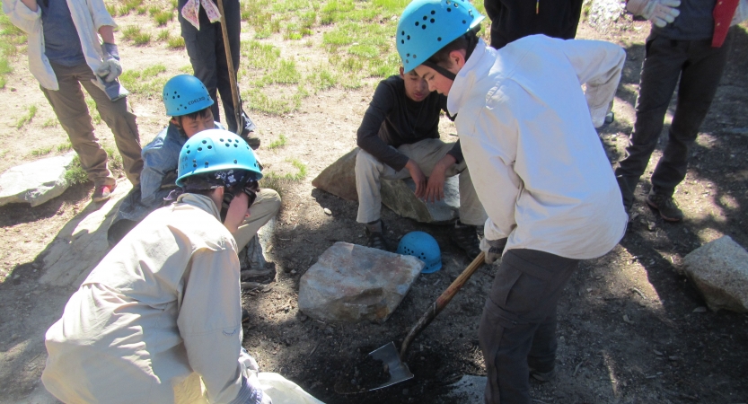 a group of students use shovels to dig during a service project with outward bound